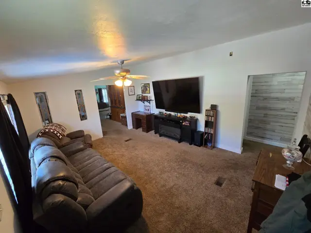 Spacious living room features a large sectional sofa, entertainment center, and textured accent wall.