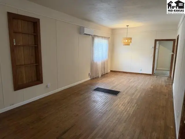 Spacious living area with hardwood floors, built-in shelving, and a chandelier.
