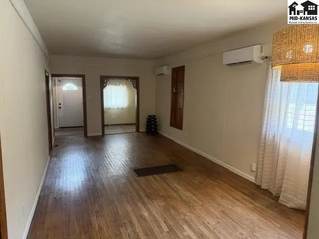 Spacious living area with hardwood floors and large windows.