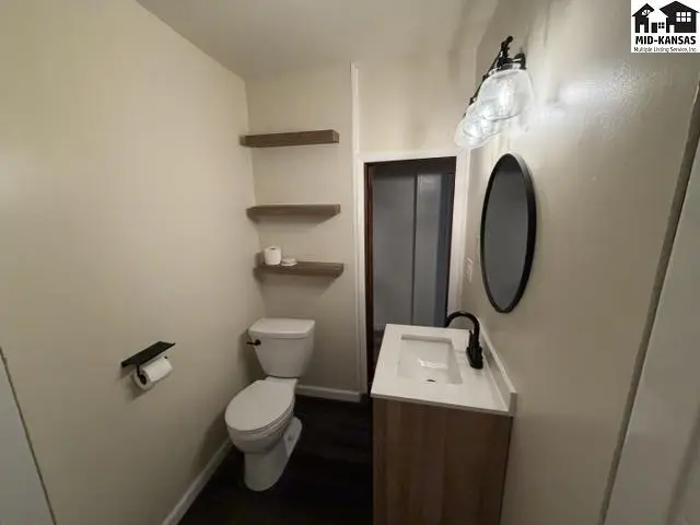 This bathroom features a vanity, toilet, and floating shelves.