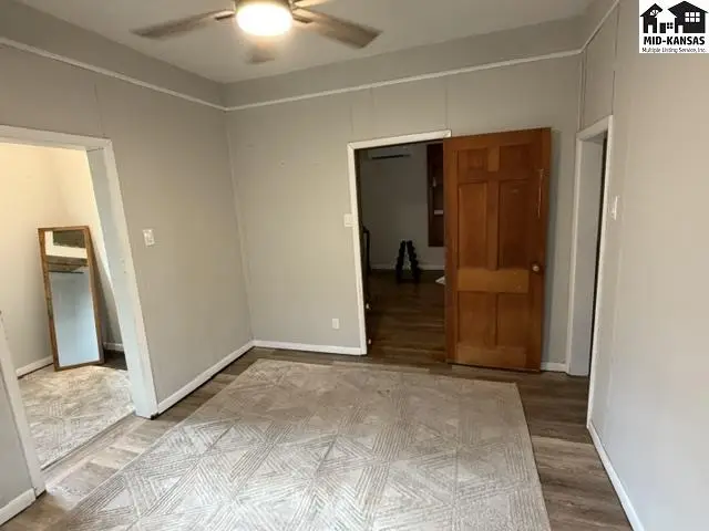This room features a ceiling fan, light grey walls, and a large area rug.