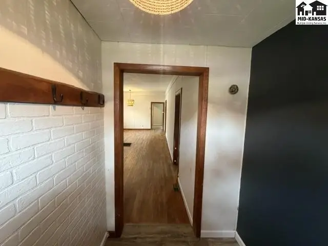 Wood-paneled hallway with white brick wall and dark accent wall leads to rooms.