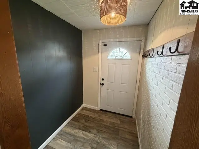 This entryway features wood-look flooring, a white door with a half-round window, and a decorative ceiling light.