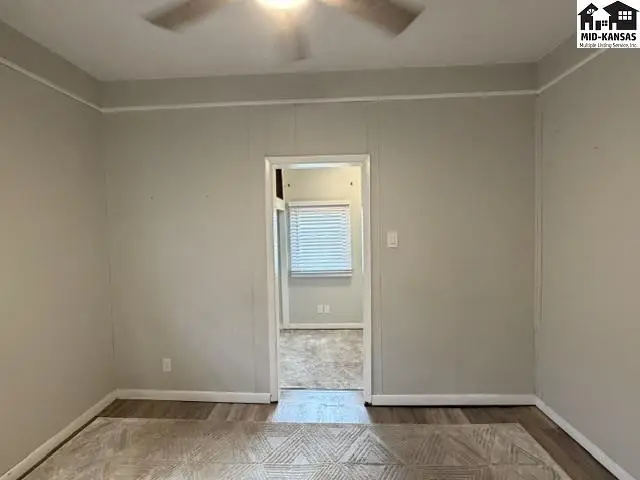 This room features neutral walls, a ceiling fan, and an opening to another space.