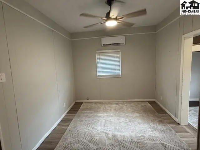 This room features neutral walls, a ceiling fan, and a large area rug.