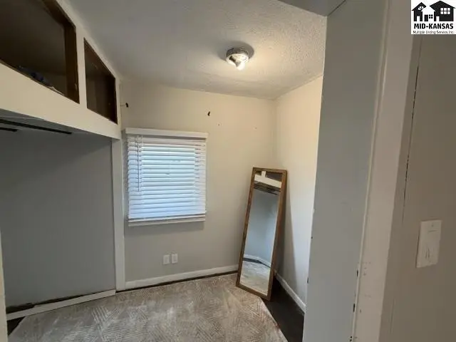 This room features a carpeted floor, a window with blinds, and built-in shelving.