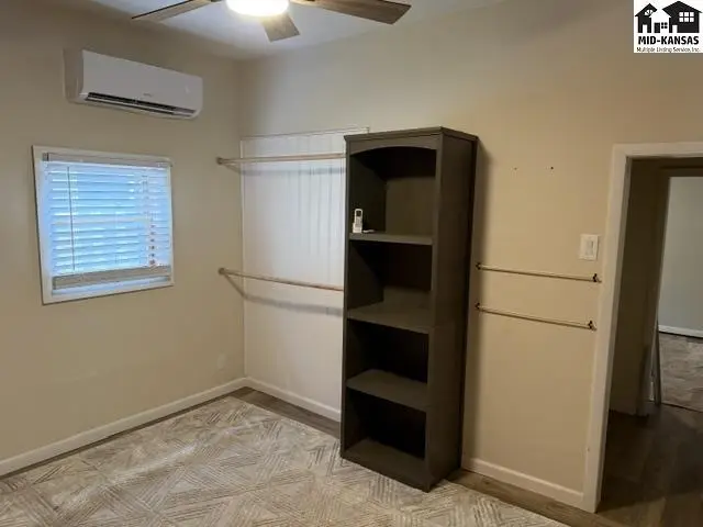 This room features a window, air conditioning unit, and a tall bookshelf.