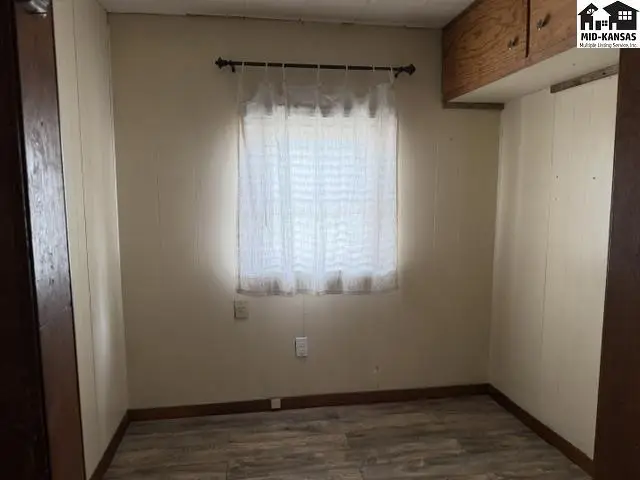 This room features light-colored walls, wood-look flooring, and a window with white curtains.
