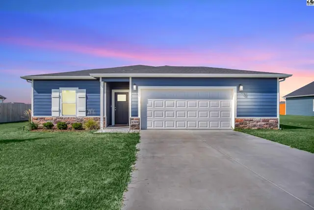 This blue-sided home features a two-car garage and a manicured lawn.