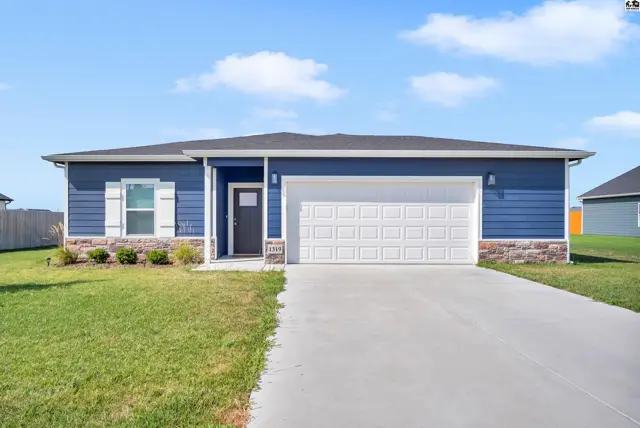 This single-story home features blue siding, a white garage door, and a concrete driveway.