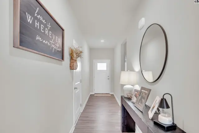 This hallway features dark wood flooring, white doors, and a console table with decorative items.