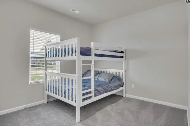 This room features a white bunk bed with blue bedding and a window with blinds.