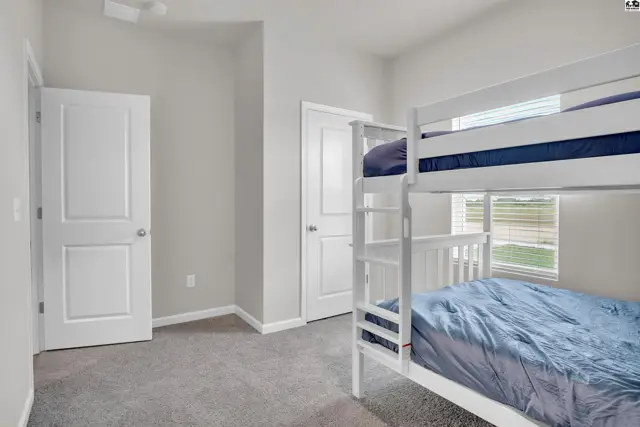 This room features a white bunk bed, two doors, and carpeted floors.