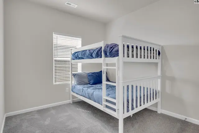 This room features a white bunk bed with blue bedding and a window with blinds.