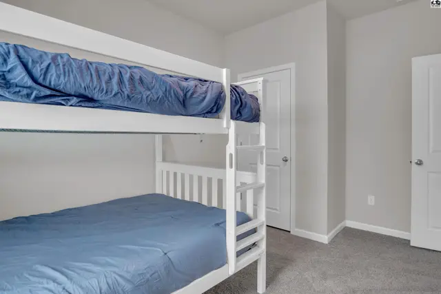 This room features a white bunk bed with blue bedding and grey carpet.