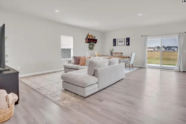 Spacious living area with light wood-look flooring and a sliding glass door.