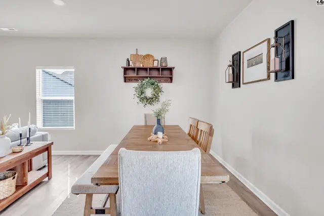 This dining area features a wooden table with bench and chairs, and a decorative shelf.