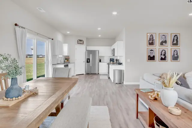 Open-concept living area with a dining table, kitchen with stainless steel appliances, and a living room.