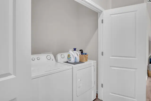 White stacked washer and dryer with laundry detergent in a laundry room.