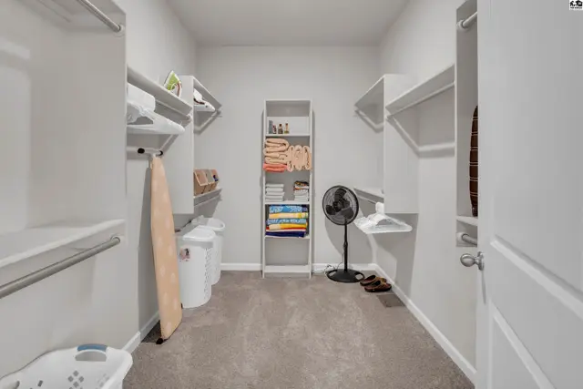 Spacious walk-in closet with ample shelving, hanging rods, and a central storage unit.