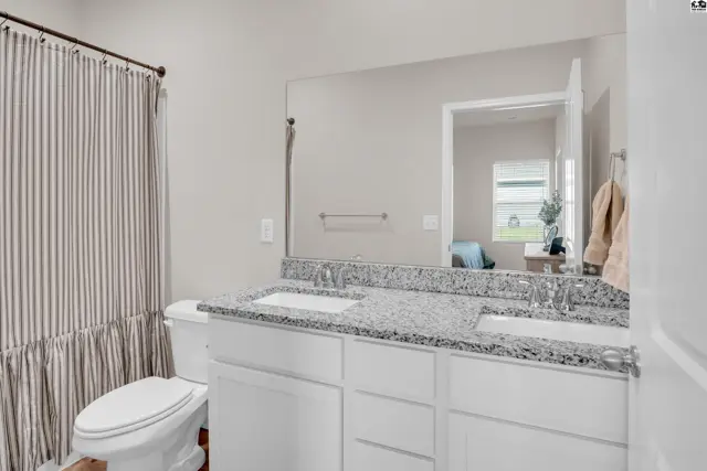 This bathroom features a granite-topped vanity with two sinks and a large mirror.