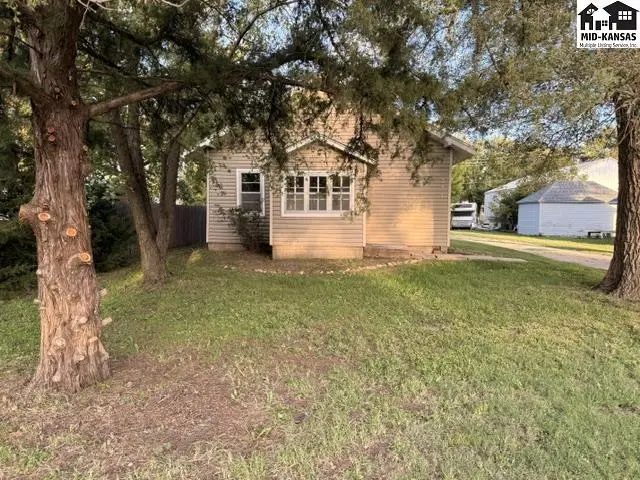 This light-colored siding home features a covered front porch and mature trees.