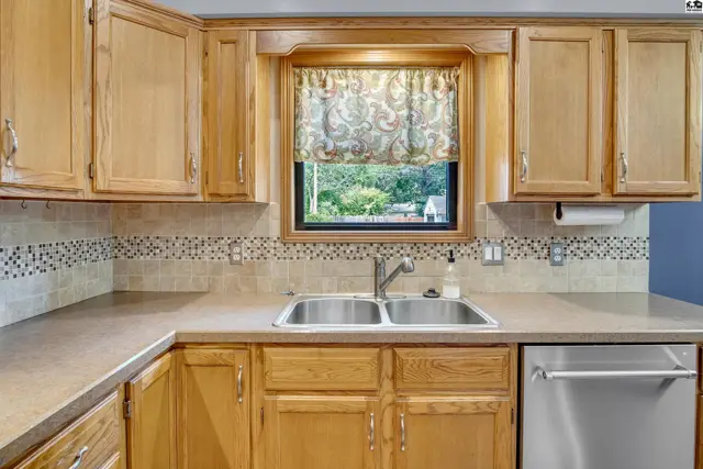 Kitchen features light wood cabinetry, a double sink, and a decorative tile backsplash.