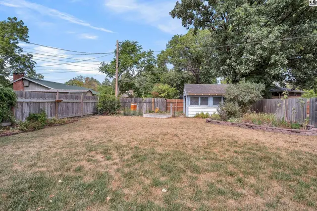 Fenced backyard with a small shed and raised garden beds.