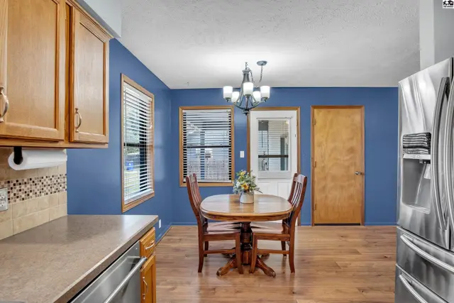 This dining area features wood floors, a chandelier, and a door leading outside.