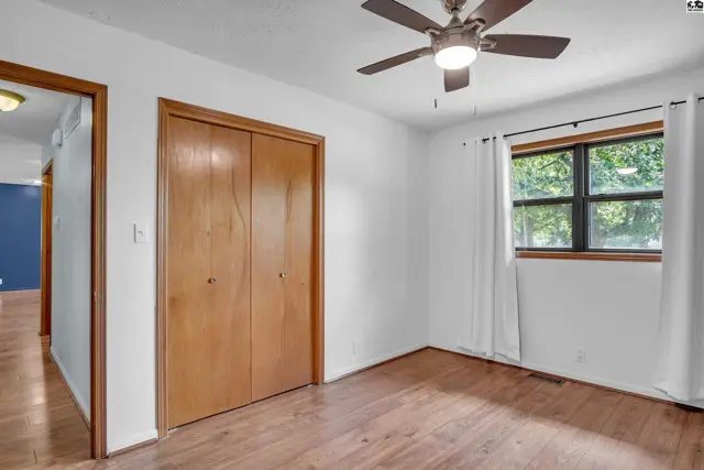 This room features a ceiling fan, wood-look flooring, and a double closet.
