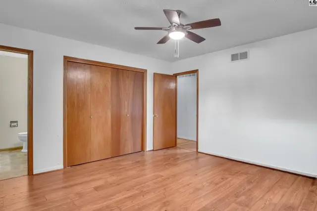 Spacious room with wood-look flooring, ceiling fan, and large closet.