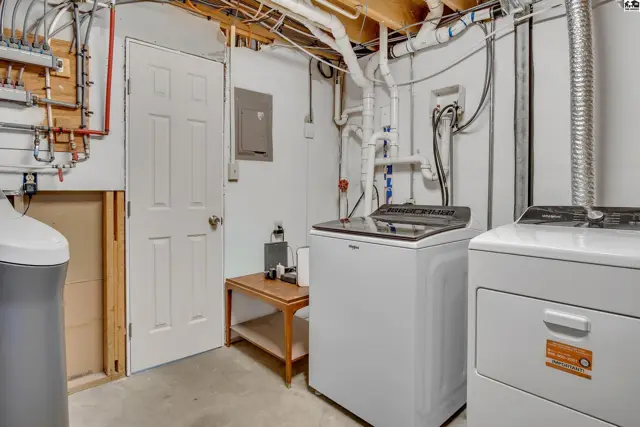 This utility room features a white washing machine, dryer, and water softener.