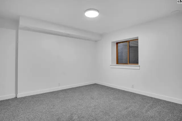 This room features neutral carpet, white walls, and a single window with blinds.