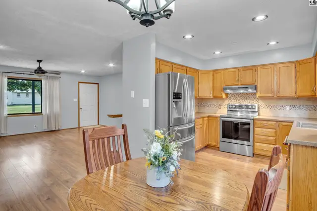 This kitchen features light wood cabinetry, stainless steel appliances, and a dining area with a round table.