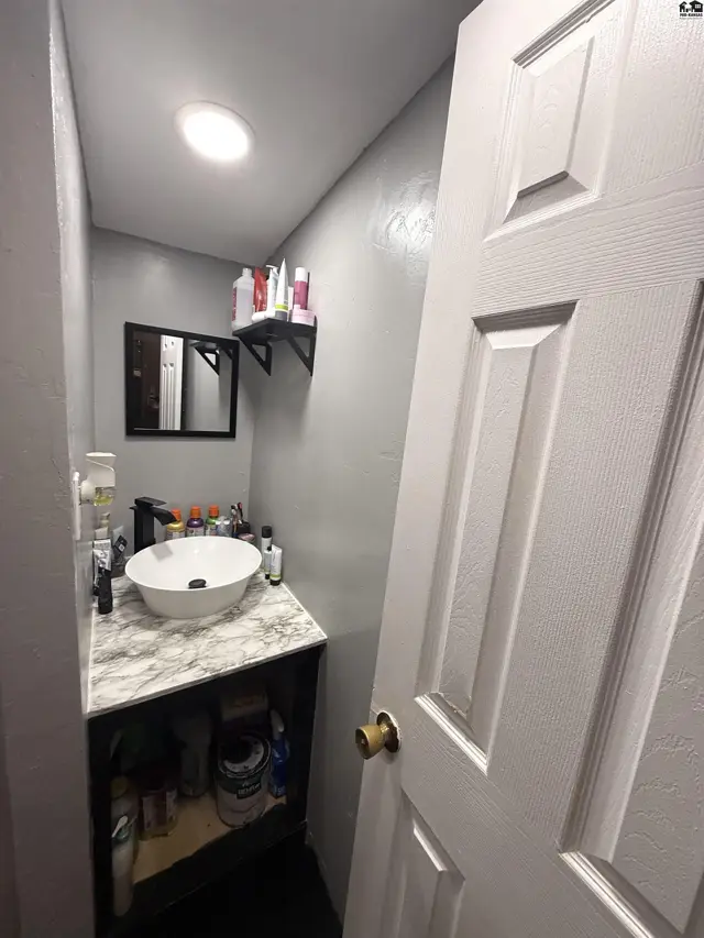 This compact bathroom features a pedestal sink, vanity, and a mirrored medicine cabinet.