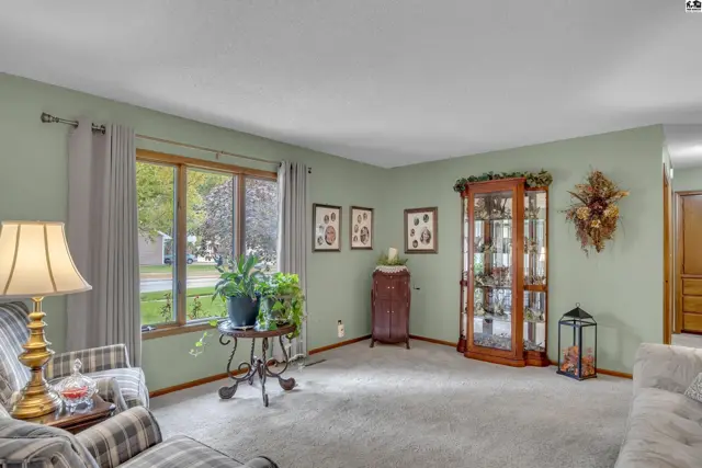 Living room features a large window, glass display cabinet, and plush carpeting.