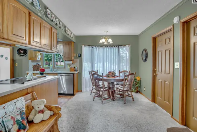 A dining area with a round wooden table and chairs adjoins a kitchen with wood cabinetry.