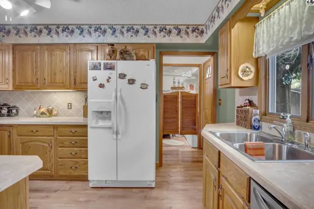 This kitchen features wood cabinetry, a white refrigerator, and a double sink.