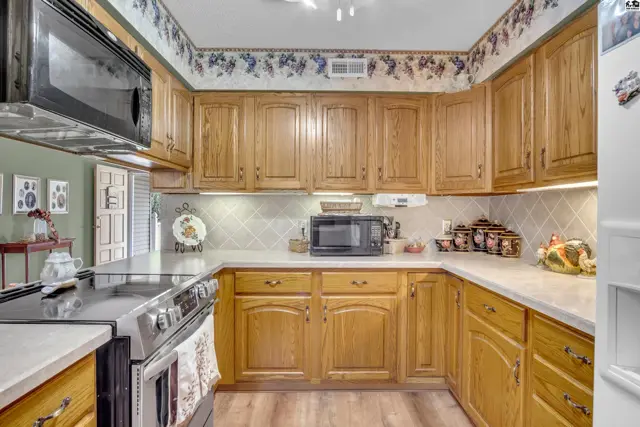 This kitchen features light wood cabinetry, white countertops, and a stainless steel range.