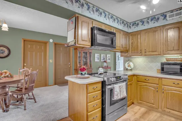 Oak cabinetry, a tiled backsplash, and a central island define this spacious kitchen.
