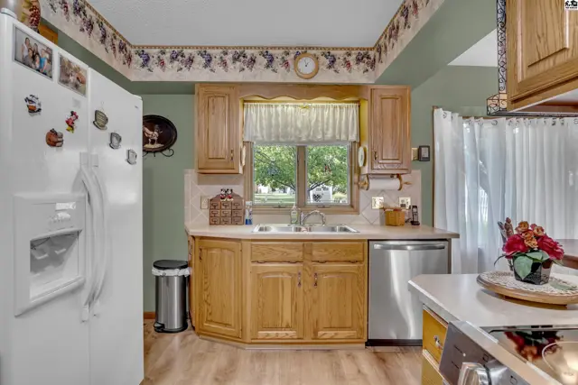 This kitchen features light wood cabinetry, a double sink, and a large window.