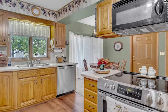 This kitchen features oak cabinetry, a stainless steel dishwasher, and a built-in microwave.