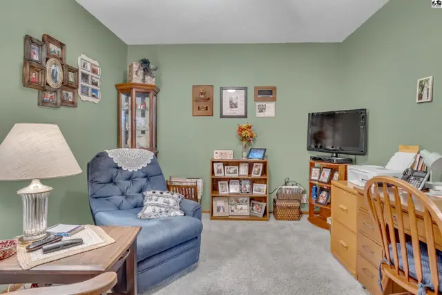 This room features a blue armchair, a wooden desk, and a television on a stand.