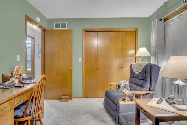 This room features a desk, a recliner, and a large closet with wooden doors.