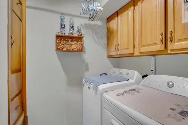 This laundry room features wood cabinetry, a built-in closet, and two appliances.
