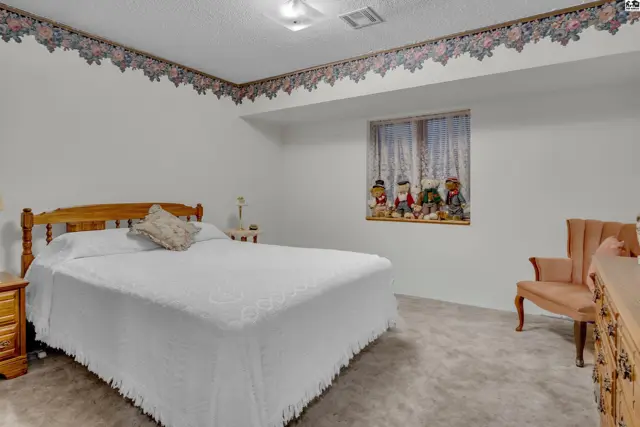 This bedroom features a wooden bed frame, a dresser, and a window with floral curtains.