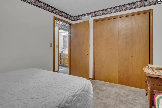This bedroom features a carpeted floor, wood-paneled closet doors, and an adjoining bathroom.