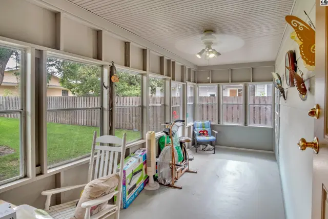 Screened-in porch with ceiling fan, windows, and a door to the yard.
