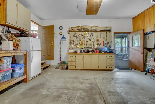This spacious garage features concrete floors, ample storage cabinets, and a workbench with tools.