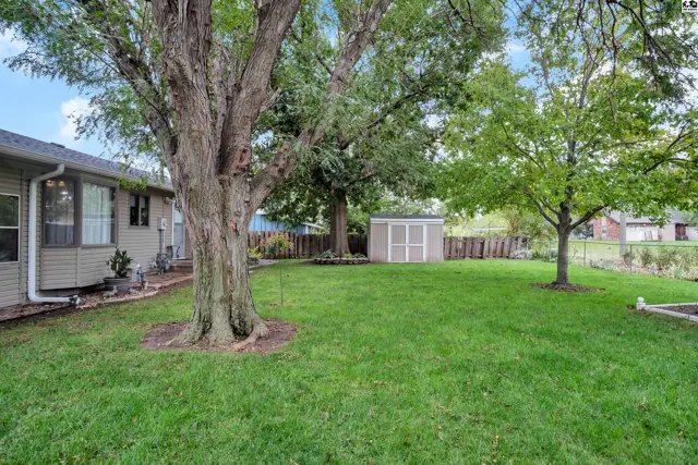 Spacious backyard features a storage shed, mature trees, and a fenced perimeter.